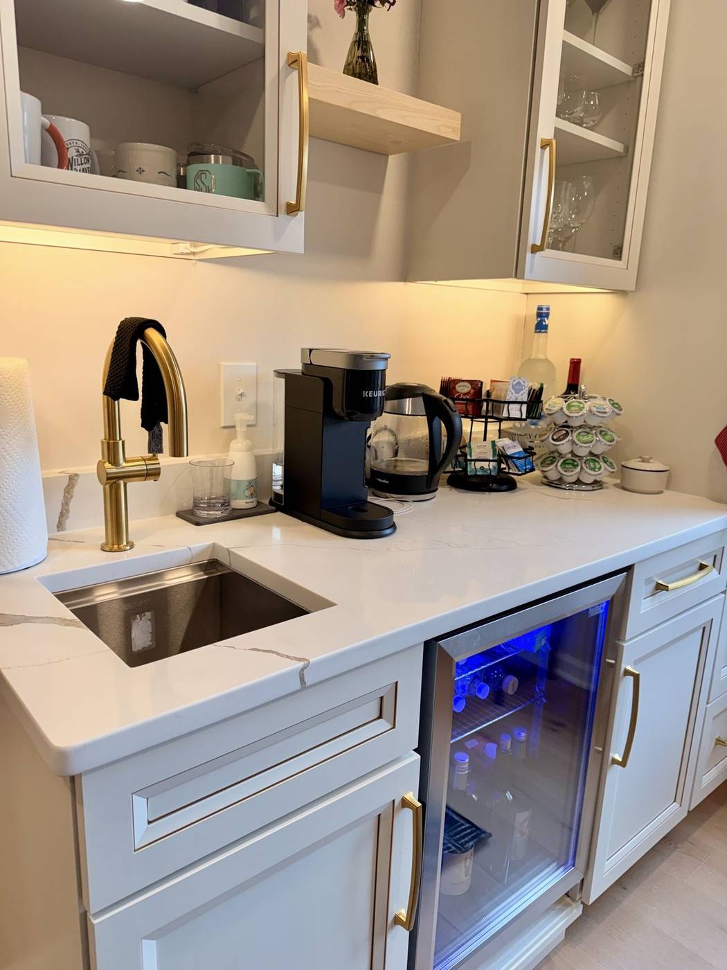 Clean white kitchenette with a polished sink and beverage refrigerator