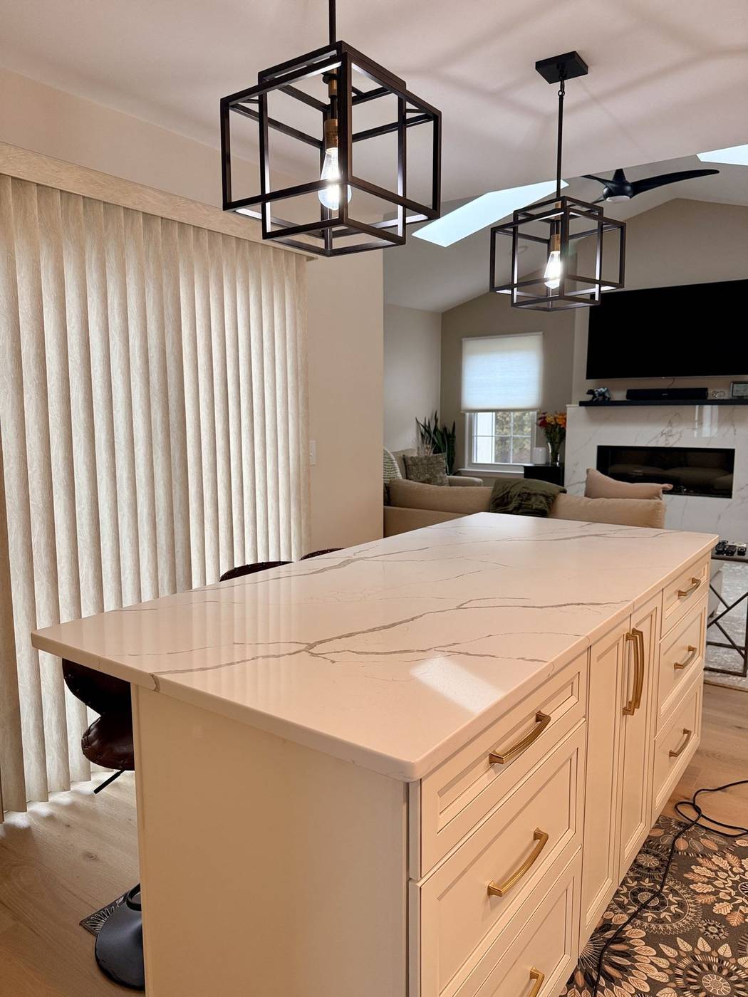 Polished white kitchen island beneath pendant lights